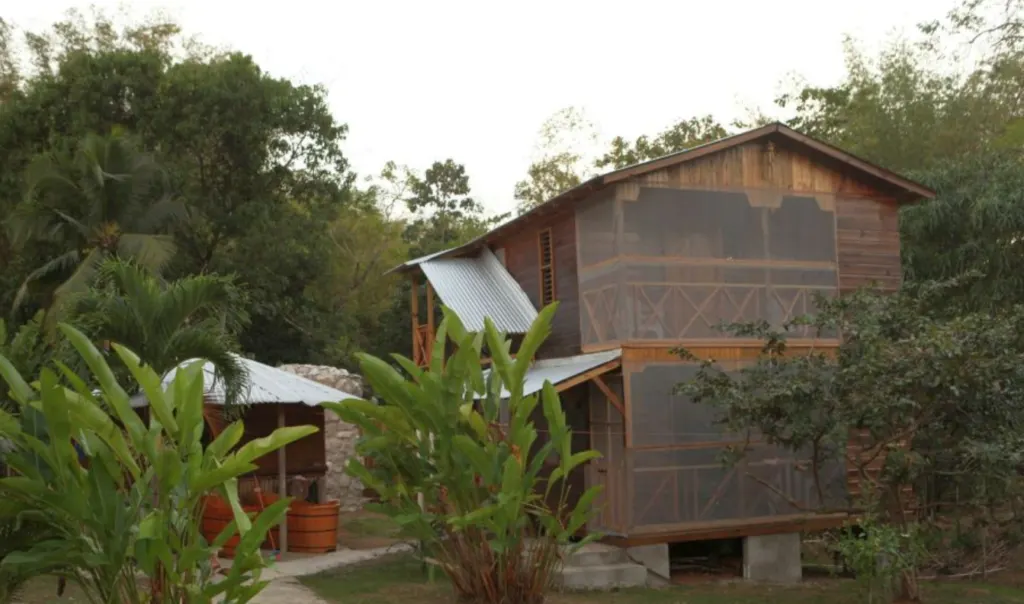 Image of a wooden cabin surrounded by plants and trees, inserted in a post about eco lodges and eco resorts in the Caribbean