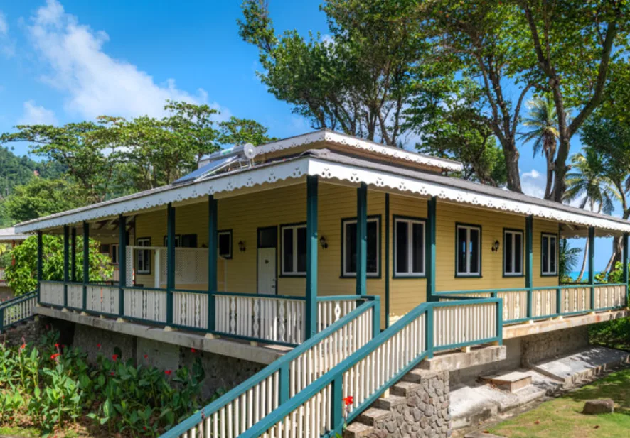 Image of a yellow and blue cabin surrounded by trees, inserted in a post about the best eco lodges and eco resorts in the Caribbean