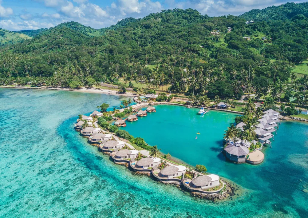 Turquoise waters dotter by villas of an eco resort in Fiji, and in the background there's dense vegetation