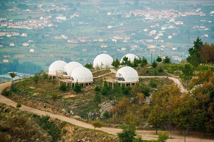 Image seen from afar of six white domes with private terraces located on an elevated position, overlooking the city 