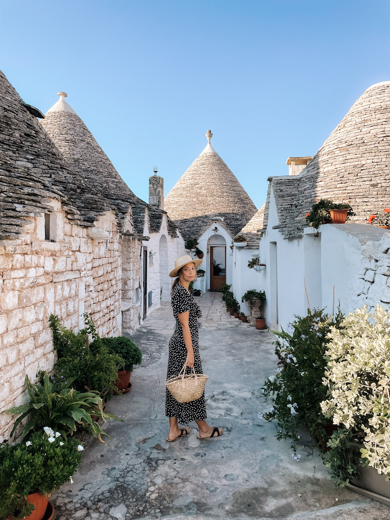 Woman standing in front of a trullo in Alberobello, Puglia.