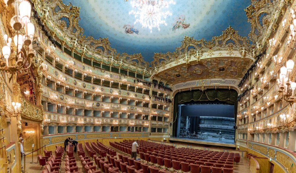 The elegant interior of La Fenice Opera House, with the stage in the back and its empty seats  being cleaned by staff