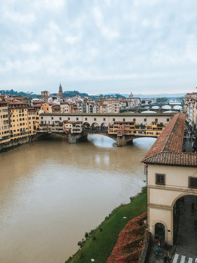 View of Ponte Vecchio over the River Arno, and a couple of other bridges behind it, as well as houses lining both sides of the river