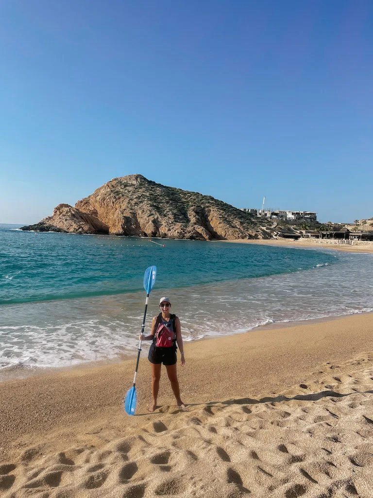 Image of a woman standing at santa Maria Bay with a paddle in her hand right before going kayaking in Cabo San Lucas.