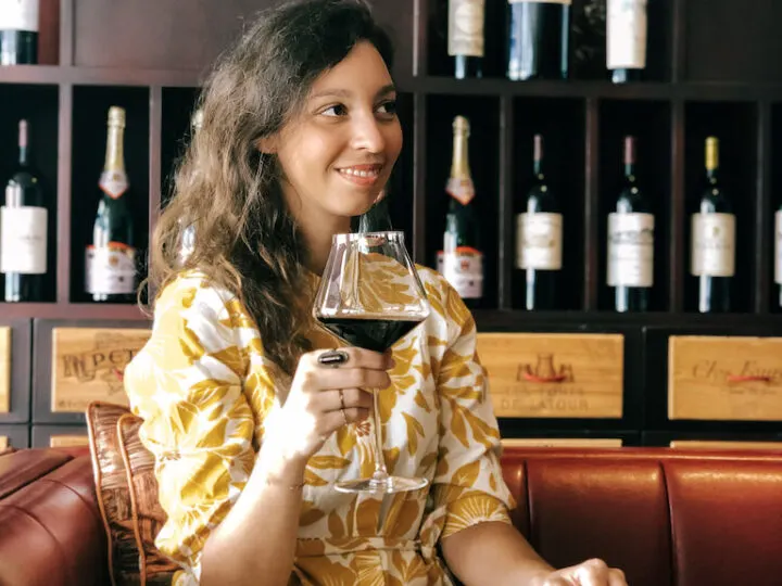 Woman with a yellow dress holding a glass of red wine during a wine tasting in Siena.