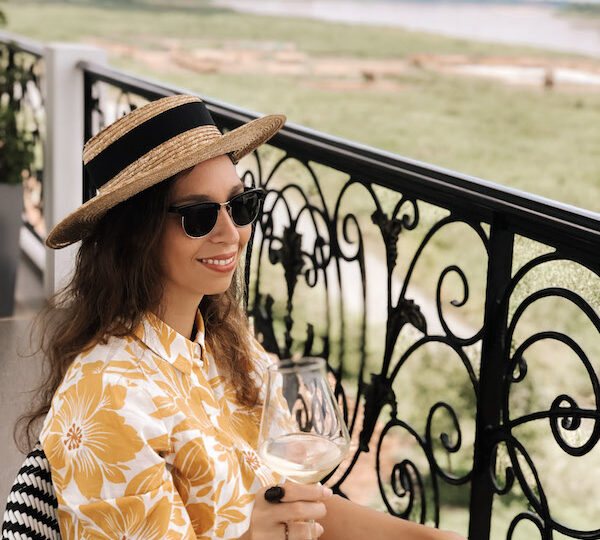 Woman with a yellow dress sitting on a balcony with a glass of white wine in her hand during a wine tasting in Rome.