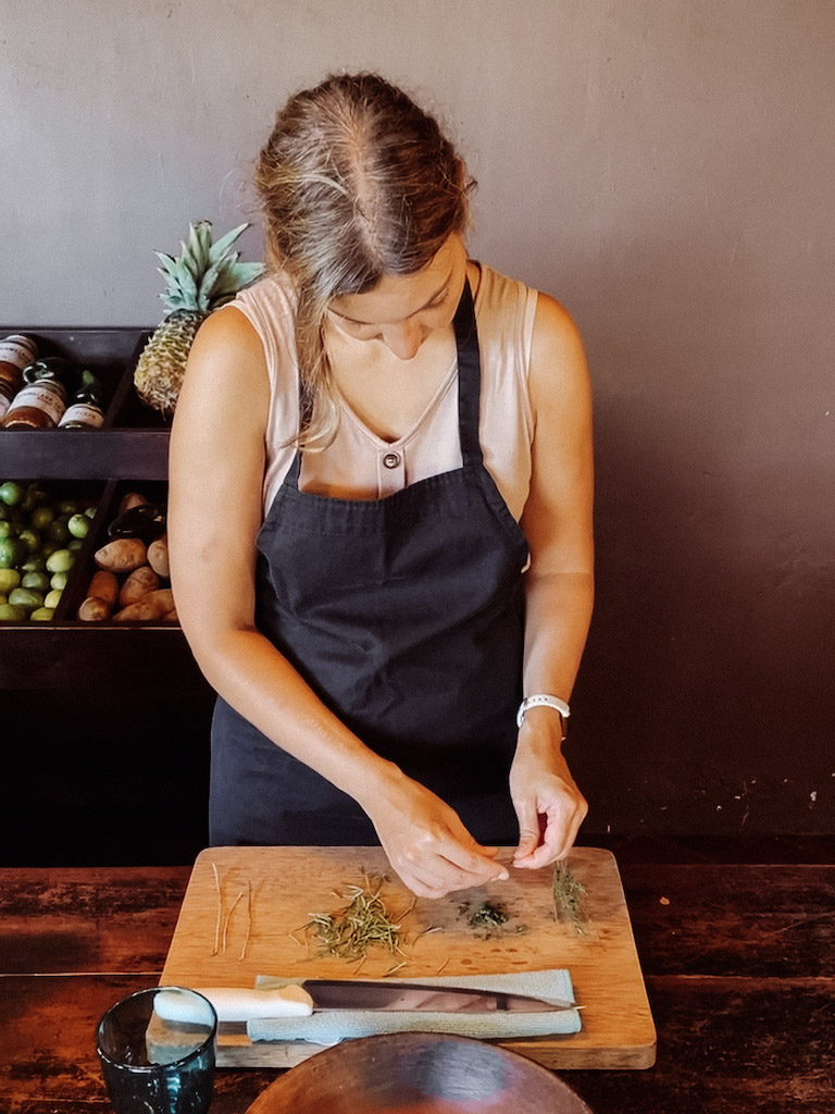 Woman with an pro cutting herbs on a wooden chopping board