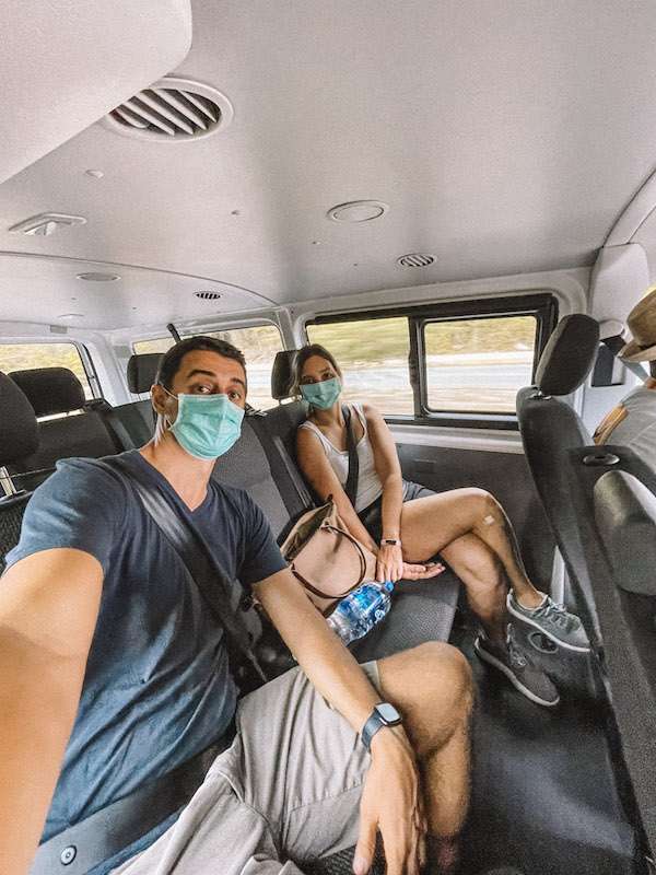 Girl and guy with face masks sitting inside a van.