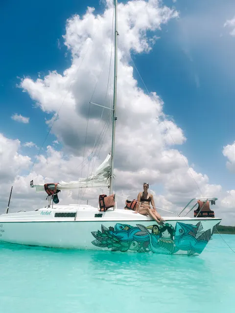 A woman lounging on a yacht, on the turquoise waters of Bacalar Lagoon