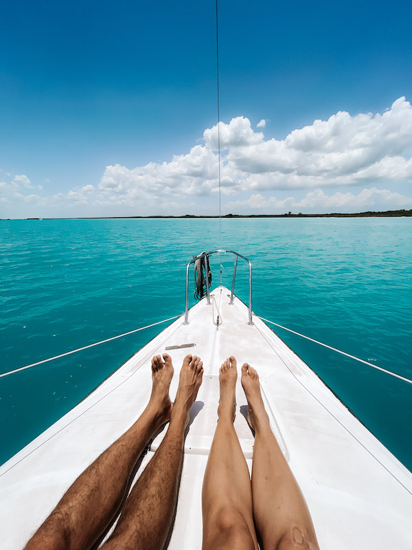 Image of a couple's legs stretched on a boat's decks, with the Caribbean Sea all around them