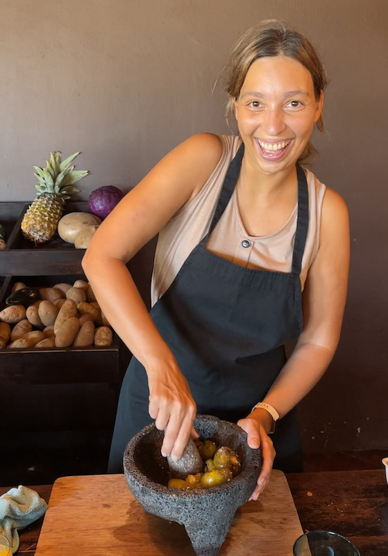 Woman looking at the camera and laughing while grinding some tomatoes during a cooking class.