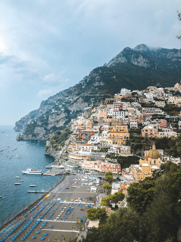 View of Positano from the road with houses perched on the mountains and the beach.