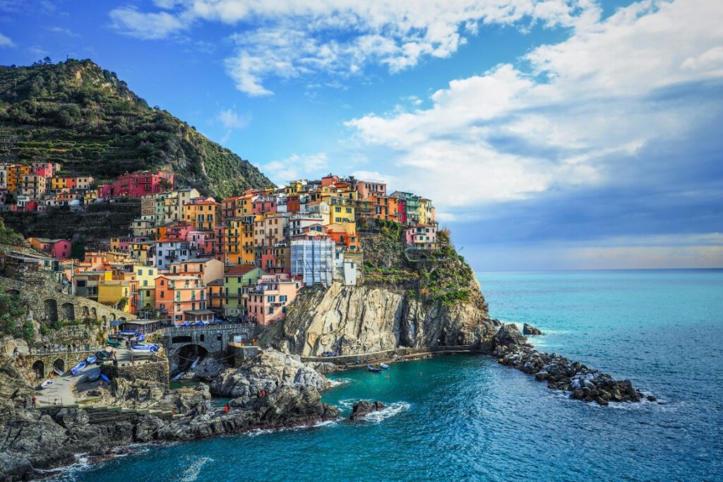 An image of colorful houses perched atop a cliff facing the sea in Cinque Terre