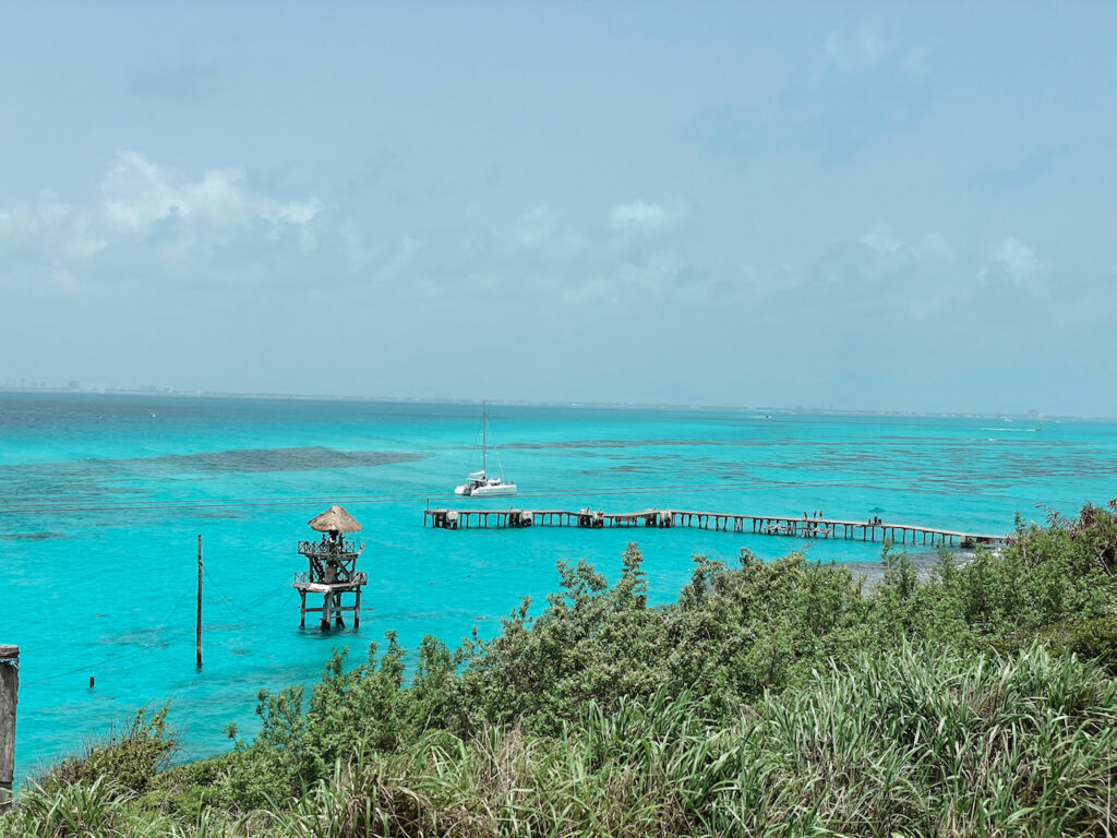 Bright blue water with a catamaran in the distance in Isla Mujeres.