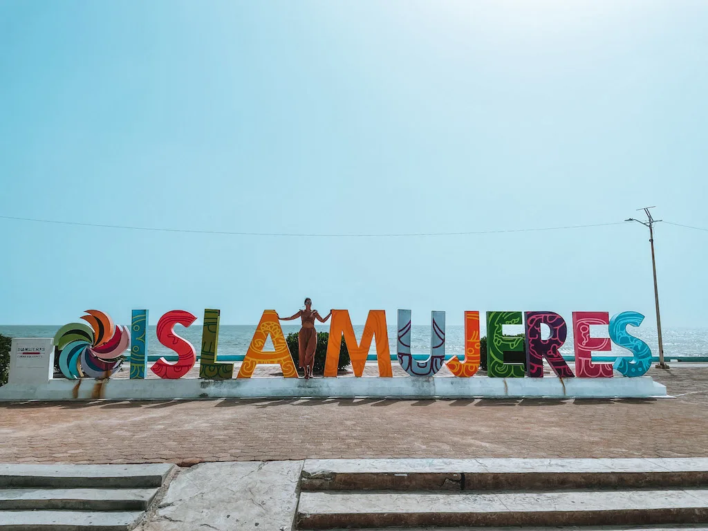 Woman standing in front of a colorful Isla Mujeres sign.