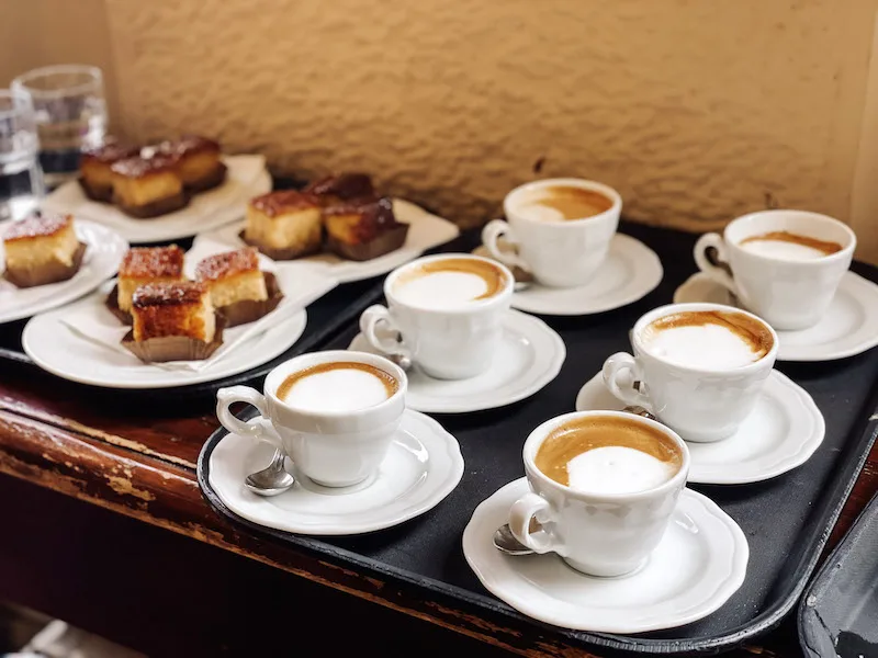 A tray with six white capuccino cups, and pieces of cake