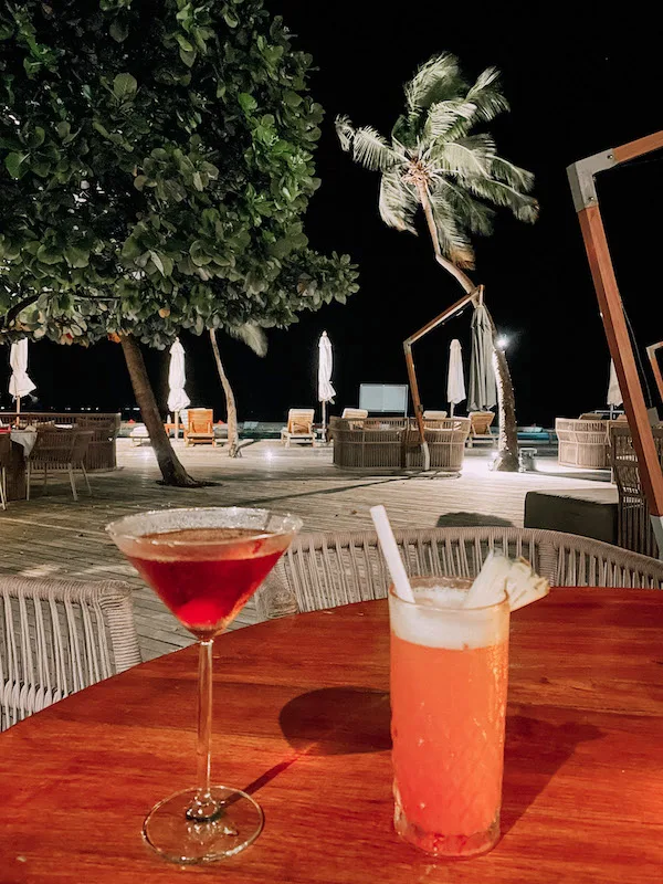 Two cocktails set on a table, and the beach behind it