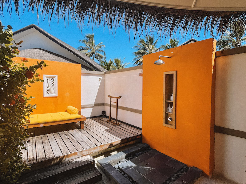 Image of an outdoor shower and wooden deck with orange walls