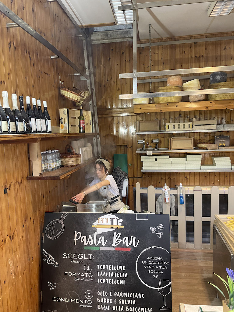 A fresh pasta stall, with a woman cooking the pasta in a big pot