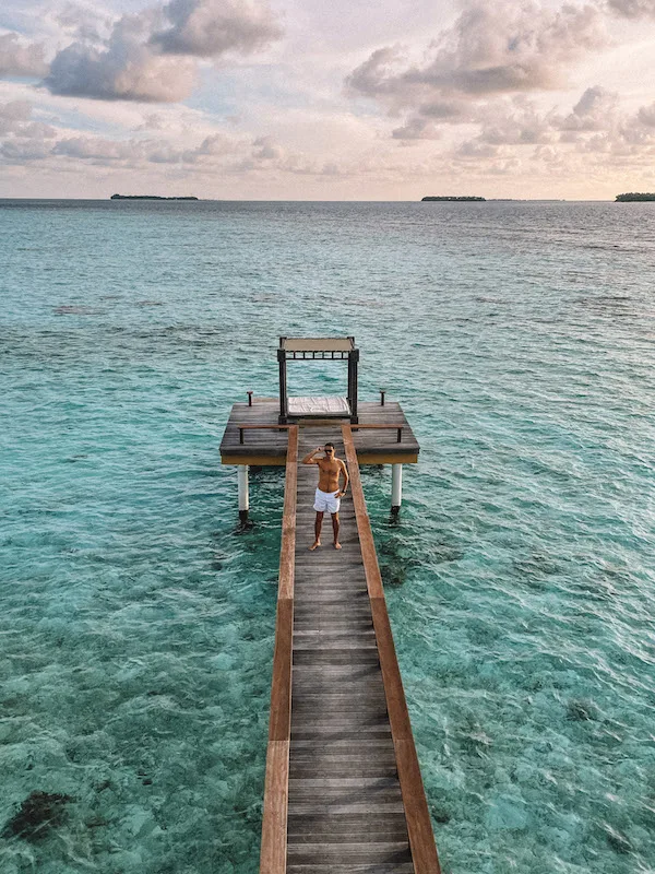 A man standing in a wooden jetty over blue waters