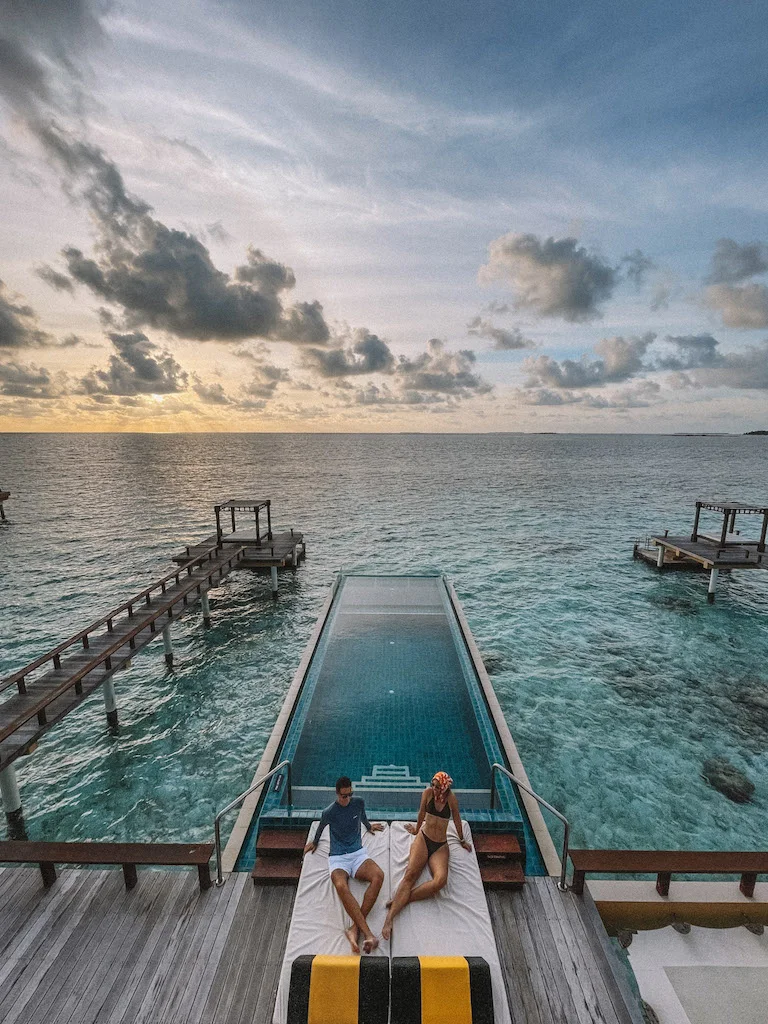 A couple sitting next to an infinity pool that overlooks the sea