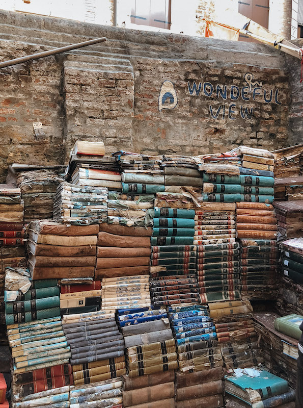 A pile of books stacked against a brick wall in Venice