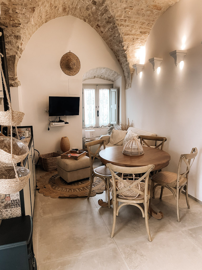 The interior of a Trulli house, with a dining table, a TV, and some furnishings