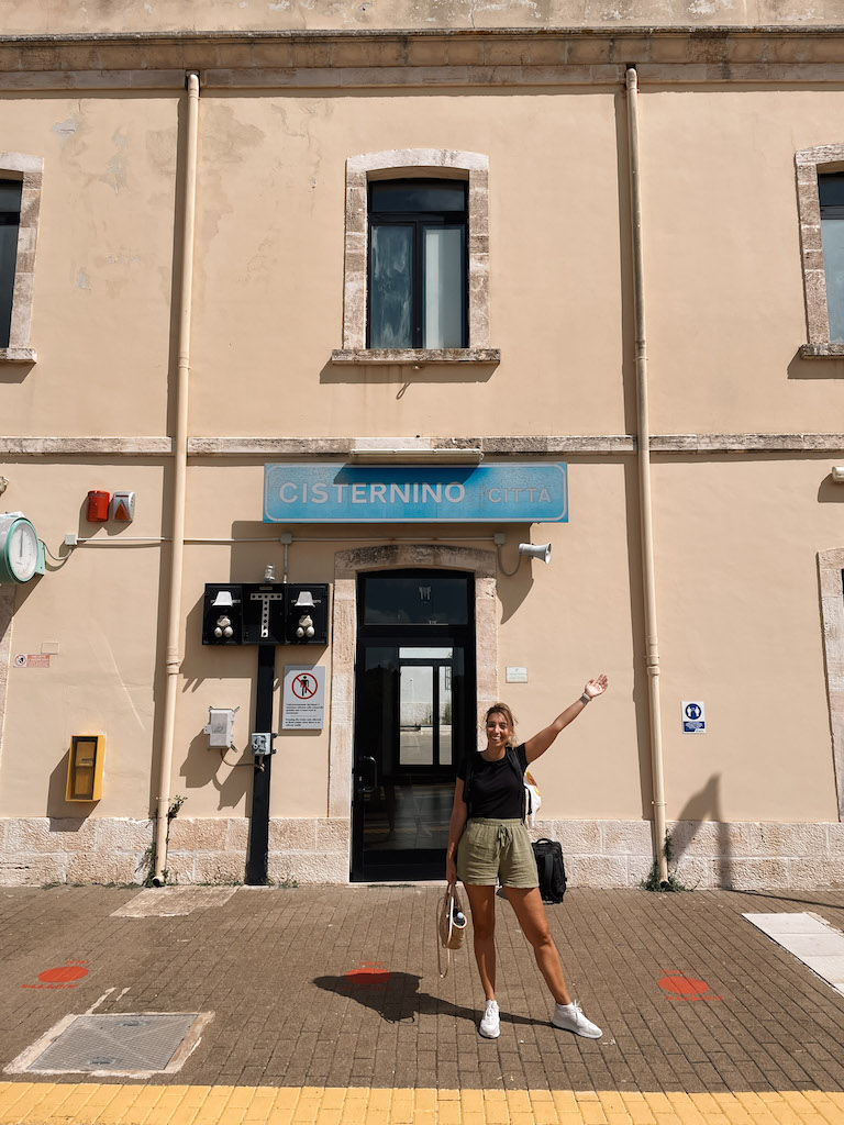 A woman standing in front of Cisternino's train station entrance