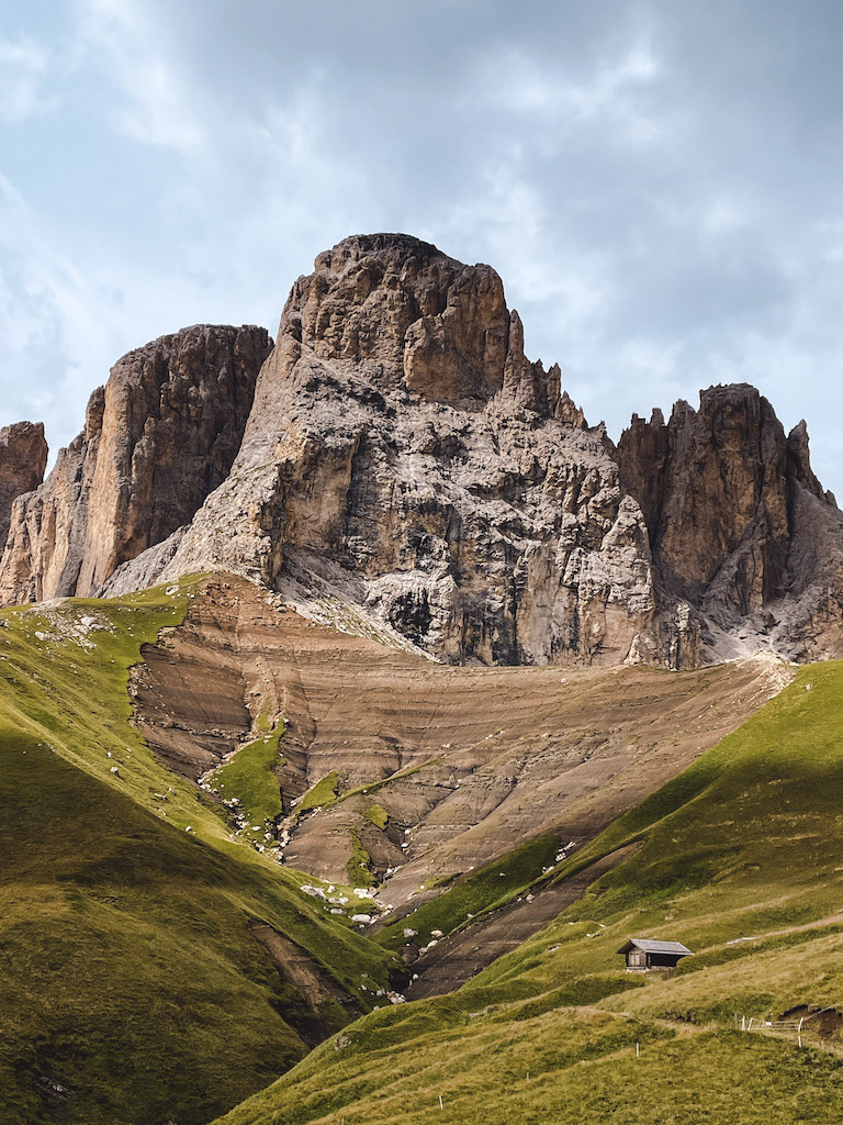 A green valley with a brown mountain in the back in the Dolomites