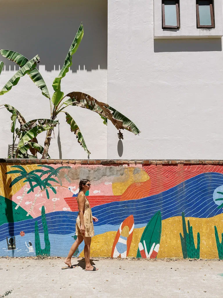 Woman walking in front of a colorful mural 