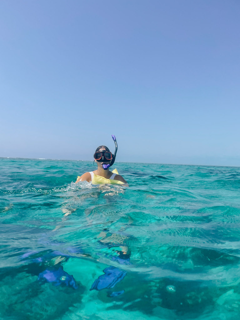 Woman with yellow lifejacket and snorkel mask swimming in the sea.