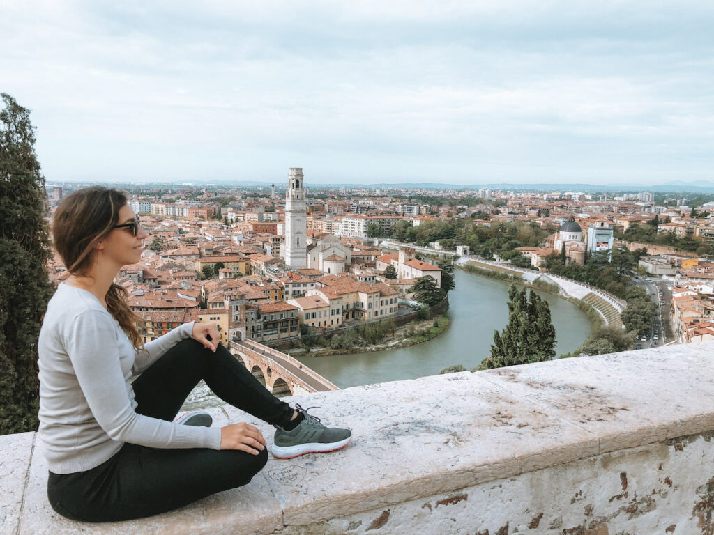 A woman sitting on a wall overlooking the city of Verona