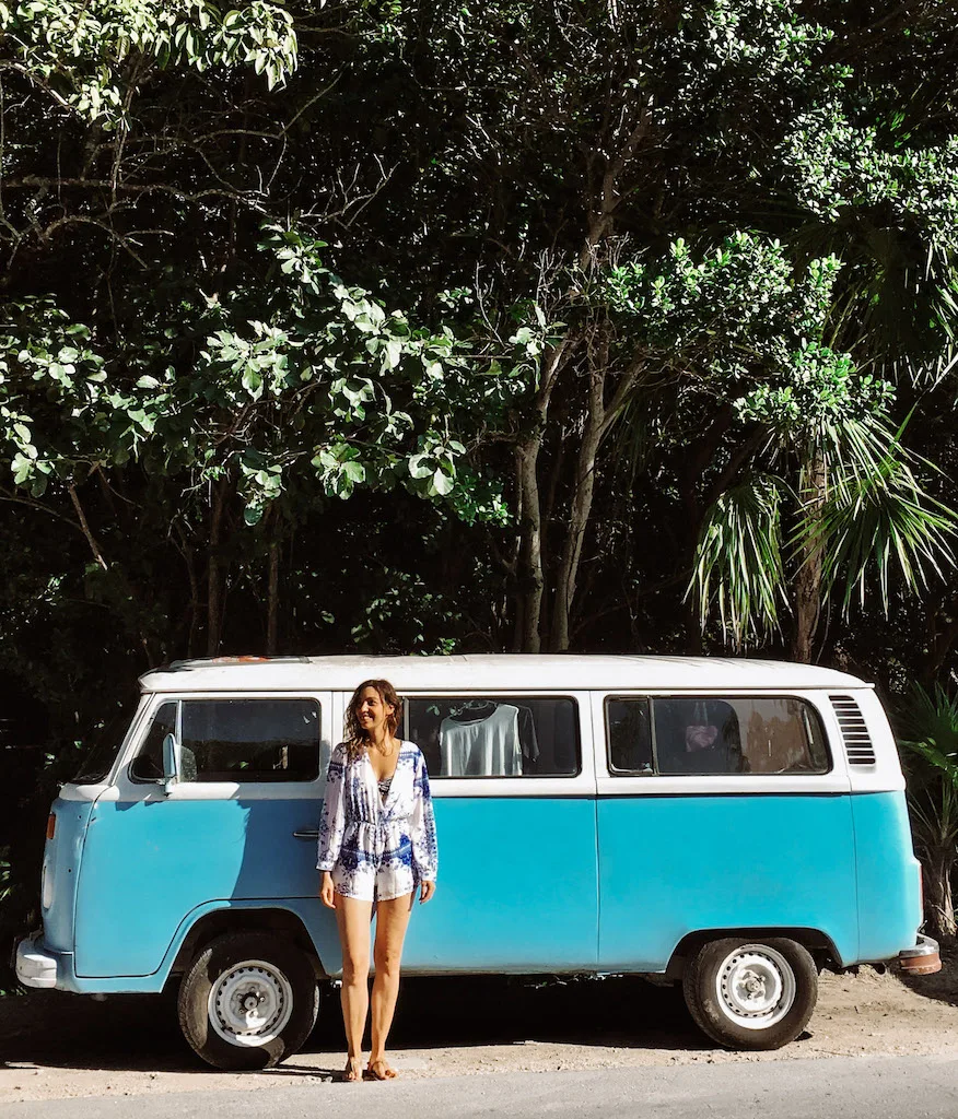 A woman standing in front of a blue and white vintage van 