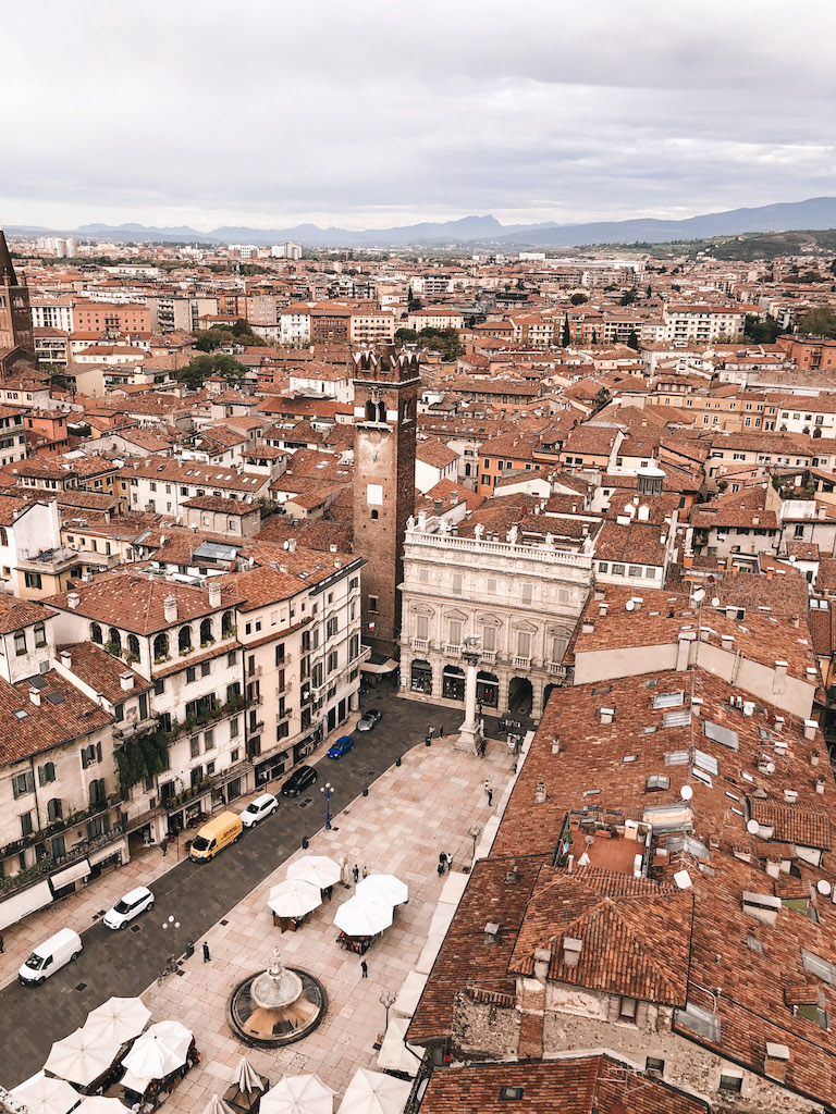 An overview image of Verona, with a sea of terracotta rooftops and mountains in the distance