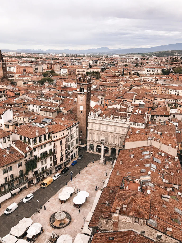 An overview image of Verona, with a sea of terracotta rooftops and mountains in the distance