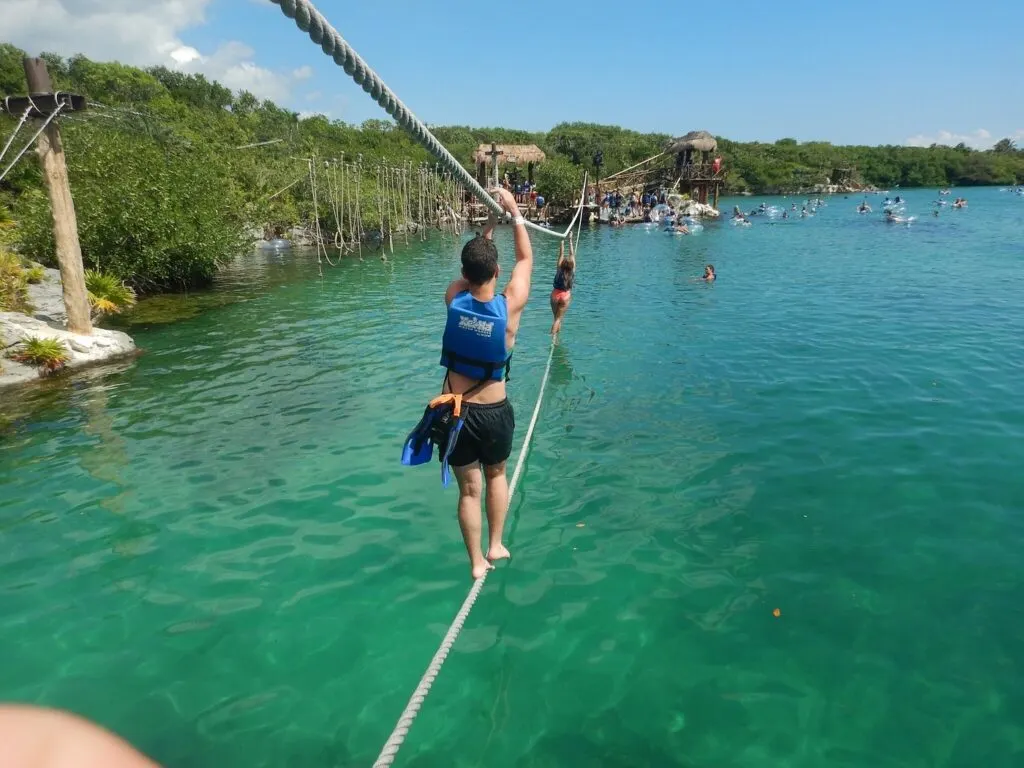 Man walking on a rop on top of the sea at Xel-Ha