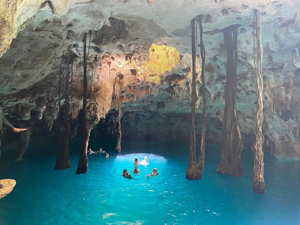 A few people swimming in a beautiful cave cenote at Xenotes.