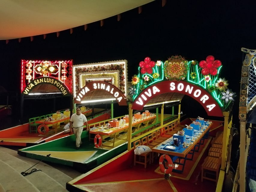 3 typical boats from Xochimilco with neon lights and tables to eat.