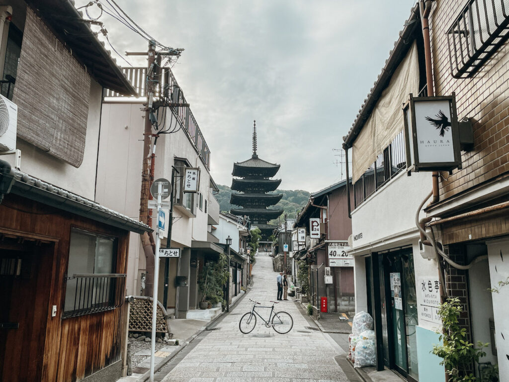 A single bike prpped up in the middle of a small street with the Yasaka Buddhist pagoda in the background.