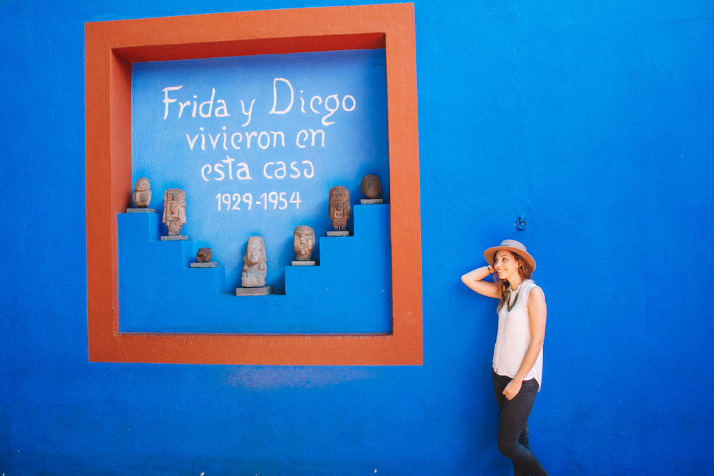 Woman with a hat standing in front one of the blue walls at Casa Azul.