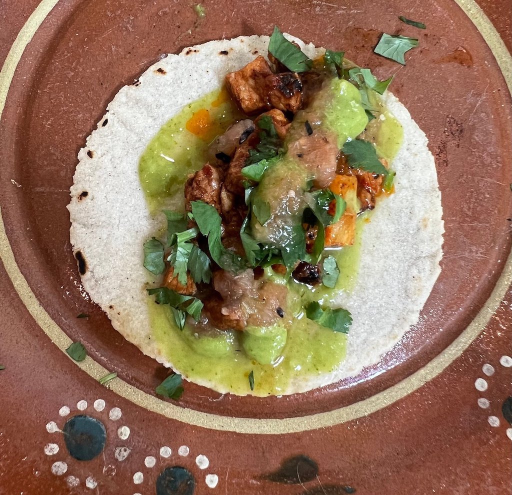 Tortilla covered with meat and a green sauce.