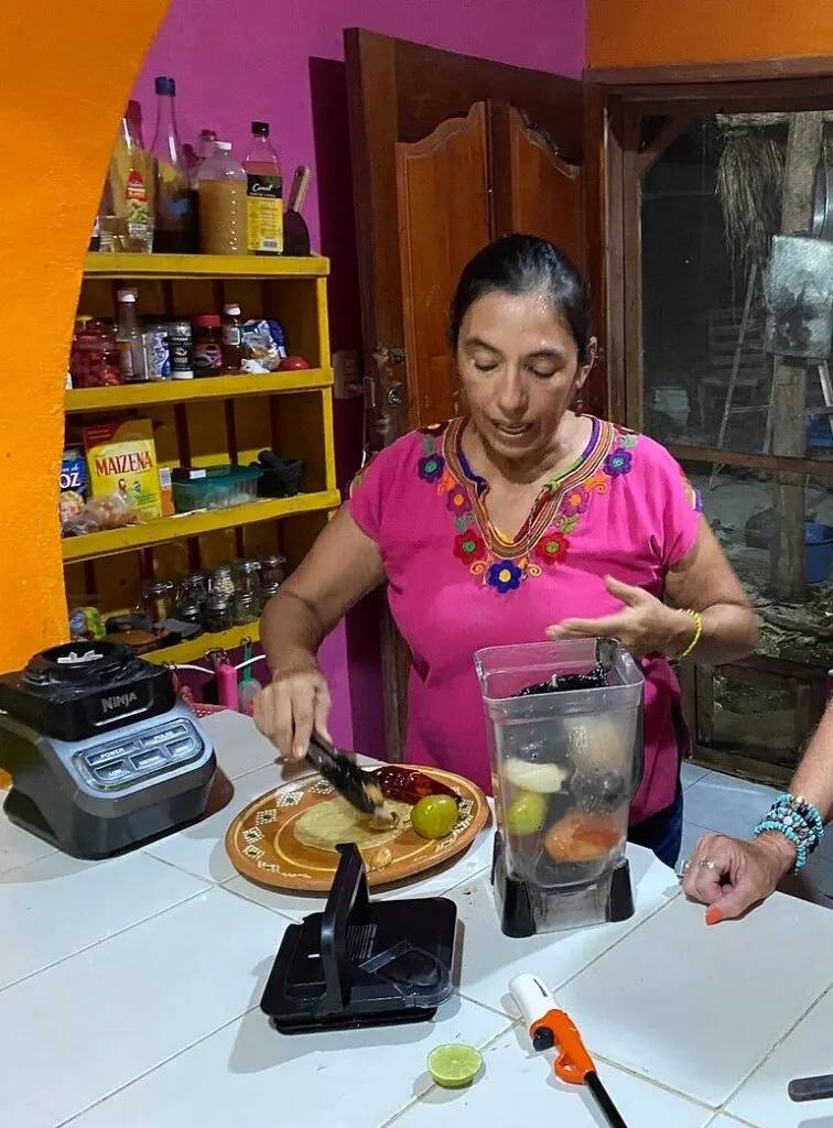 Woman with a bright pink shirt cooking a tortilla.