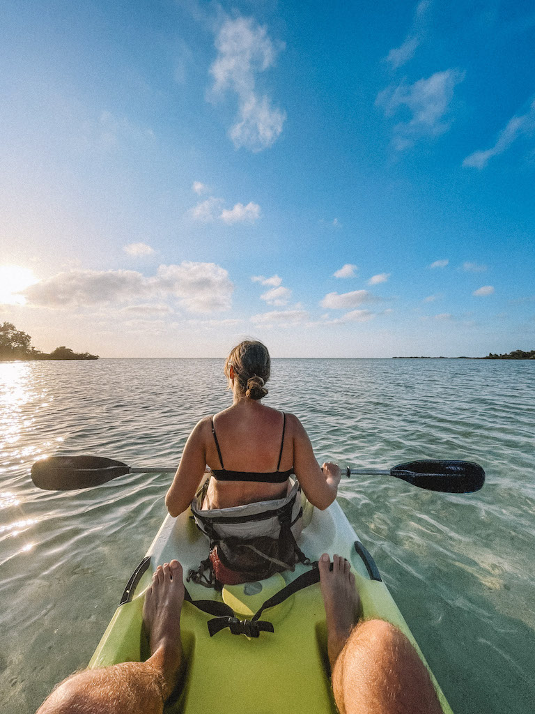 Woman kayaking in a green kayak around sunset time.