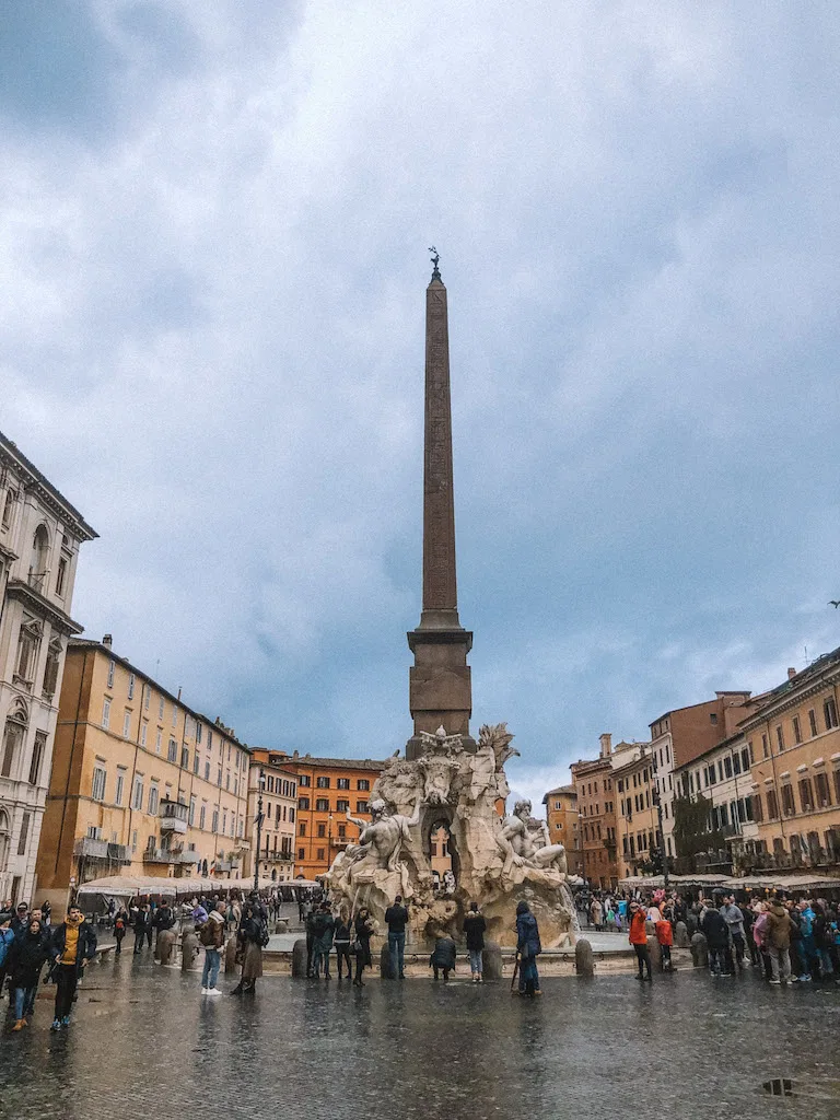 An image of Piazza Navona, with a crowd gathering around the fountain