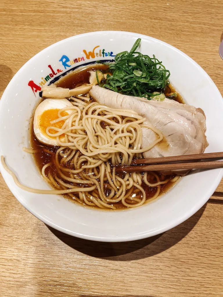 Plate of ramen with slices of pork meat, green onion and half soft boiled egg.