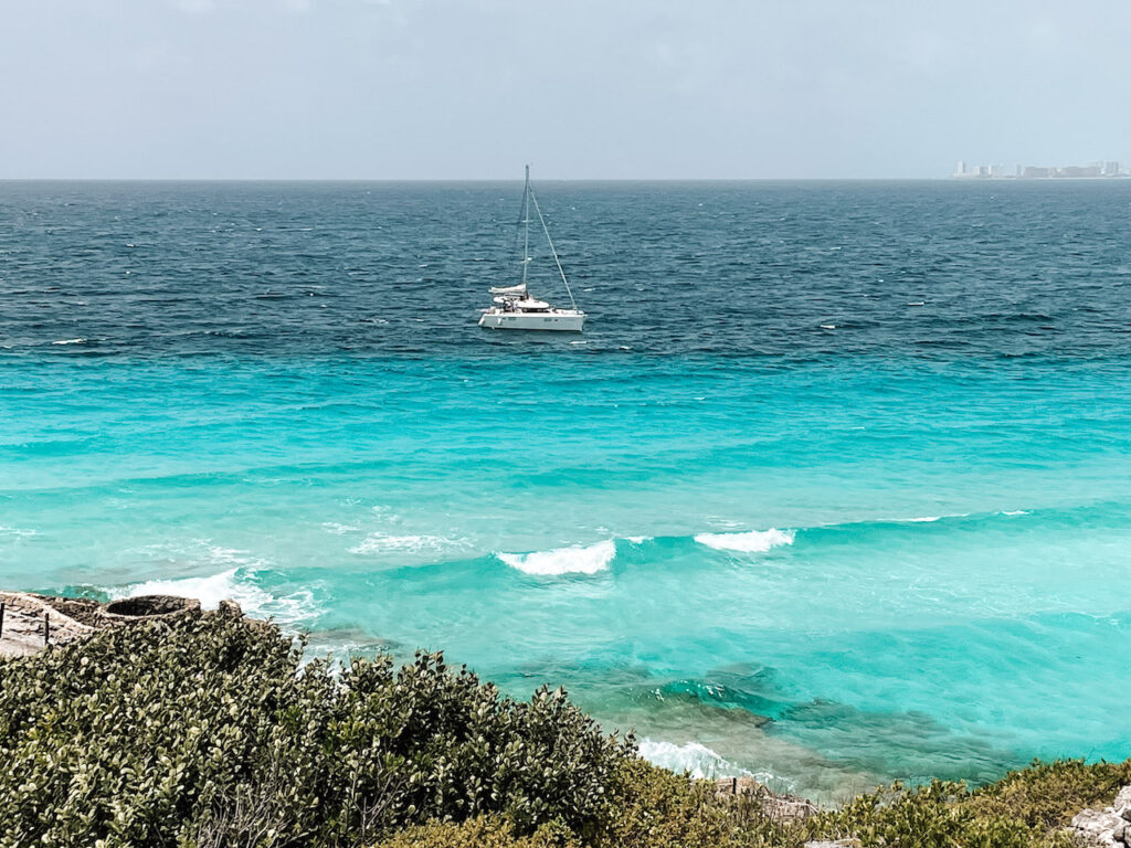 A white catamaran sailing off the coast of Isla Mujeres.