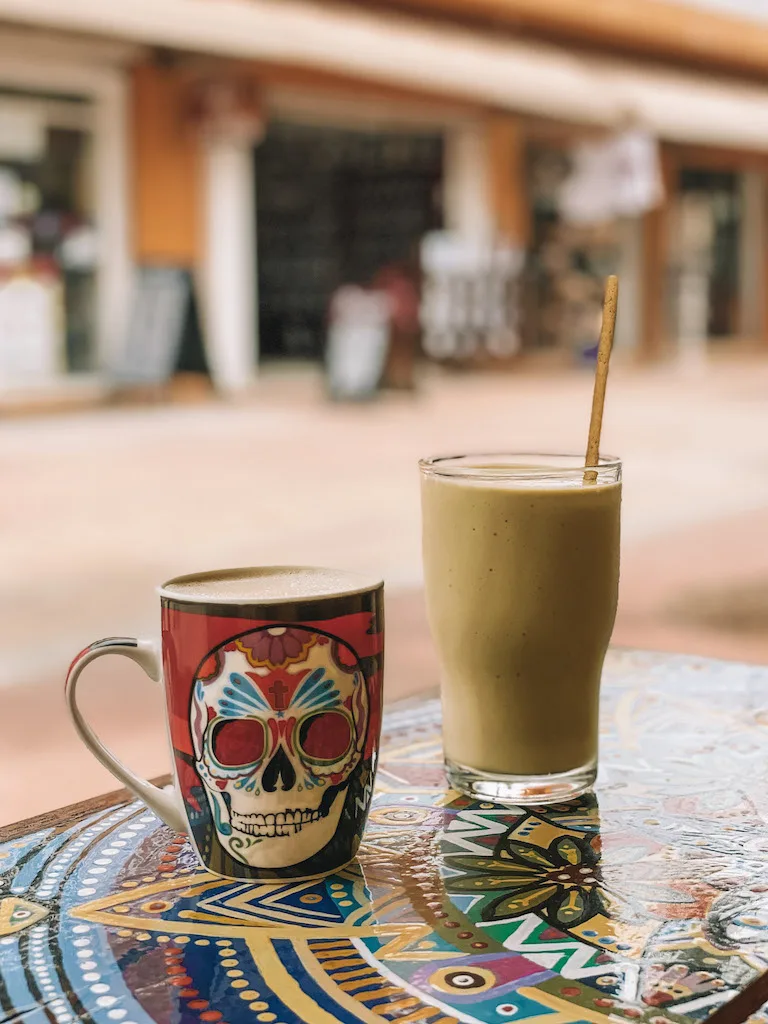 A mug of coffee and a tall smoothie glass on a table