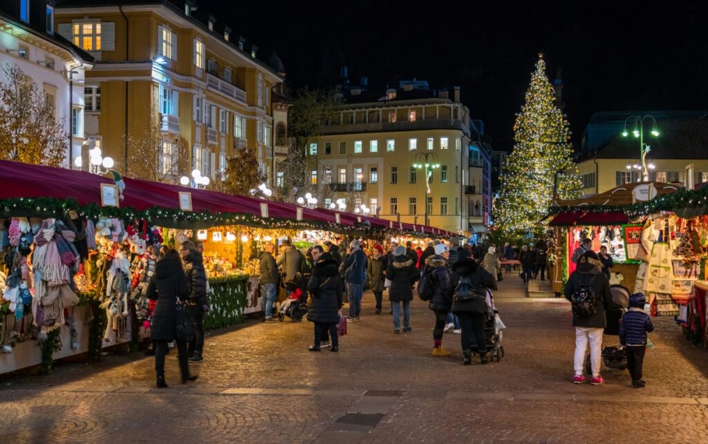 A square with a Christmas market set up, and people walking past the stalls