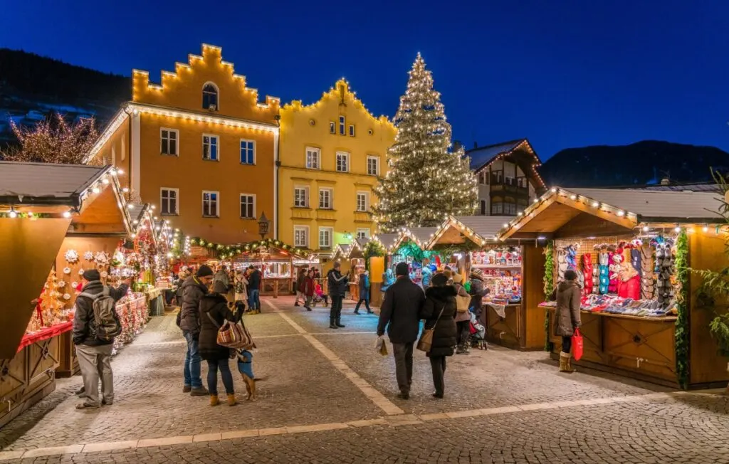 A Christmas Market with various wooden stalls and people walking around them