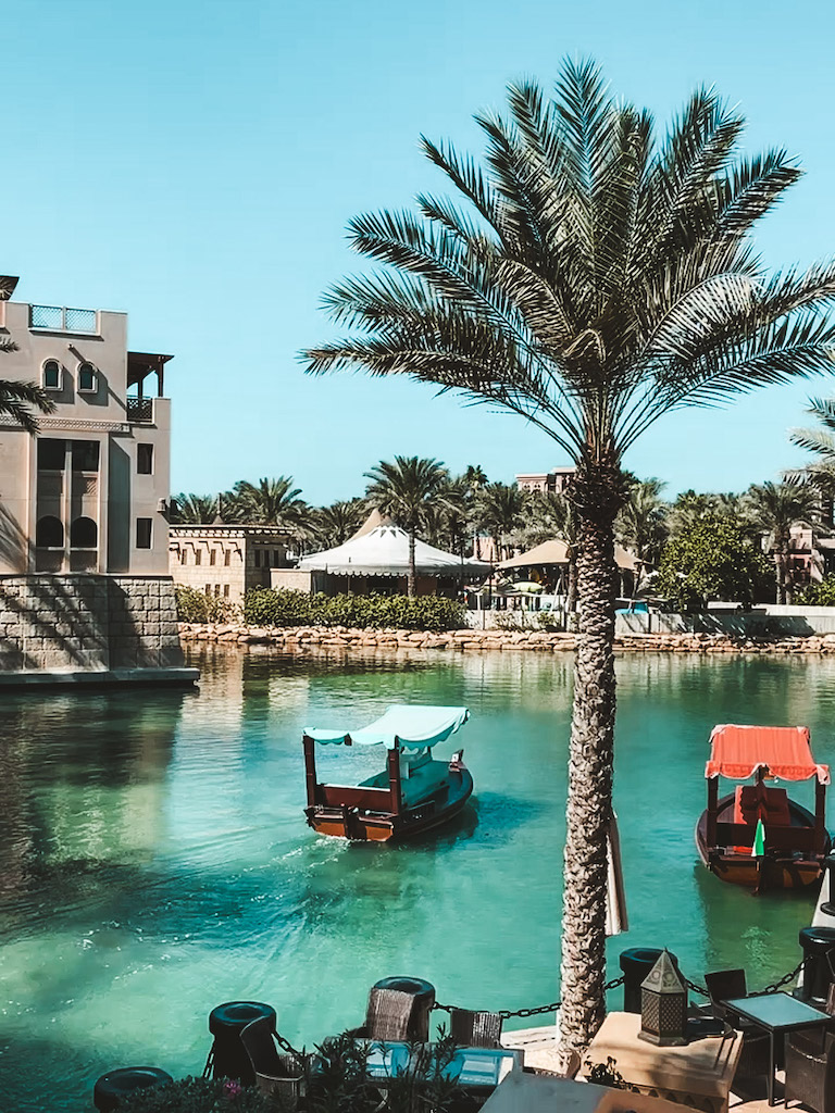 The canals around Souk Madinat Jumeirah with two boats and lined by palm trees